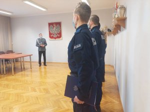 Uroczystość ślubowania w świętochłowickiej komendzie. Na zdjęciu widać Komendanta Miejskiego Policji w Świętochłowicach oraz ustawionych w szeregu  5 nowo przyjętych policjantów z dokumentami slubowania w lewej dłoni