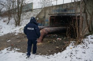 Dzielnicowy podczas kontroli rur ciepłowniczych w okolicy których mogą przebywac osoby bezdomne, szukajace schronienia przed mrozem.