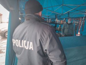 Na zdjęciu policjant dzielnicowy w trakcie kontroli stoiska z fajerwerkami