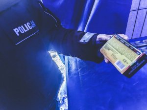 zbliżenie na pudełko z petardami trzymane w rece umundurowaego p[olicjanta podczas kontroli stoiska