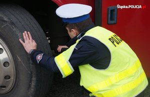 Na zdjęciu policjant w drogowki w trakcie sprawdzania autokaru przed wyjazdem dzieci na ferie