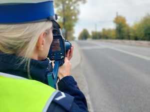 Na zdjęciu policjantka z dorgówki w trakcie dokonywania kontroli prędkości recznym, laserowym miernikiem.