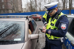 Na zdjęciu dwóch policjantów z drogowki w trakcie prowadzenia czynności przy kontroli drogowej wobec kierującego który popełnił wykroczenie