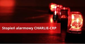 Na zdjęciu napis na czerwonym tle stopień alarmowy charlie crp, obok sygnały świetle koloru czerwonego