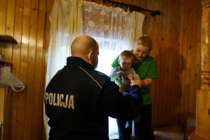 Na zdjęciu mundurowy w jednym z domów na terenie miasta, w którym przebywają uchodźcy. Policjanci wręcza dziecku  gadgety z kampnii &amp;quot;Mamo, Tato tutaj jestem&amp;quot; w postaci czapki i opaski sylikonowej.