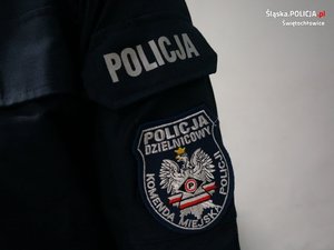 Zbliżenie na ramie policjanta na którym widać napis policja oraz naszywkę z orłem i napisem Policja Dzielnicowy Komenda Miejska Policji w Świętochłowicach