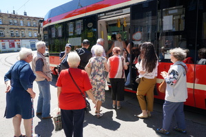Na zdjęciu widać mundurową która zaprasza seniorów do wejścia do tramwaju, w którym będzie prowadzona akcja profilaktyczna