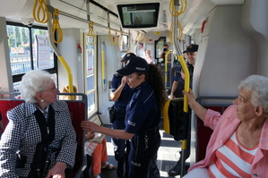 Wnętrze tramwaju, w ktorym widać mudnurowe oraz seniorów. Policjantka rozmawia z jedną z uczestniczek akcji profilaktycznej