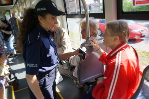 Wnętrze tramwaju. Policjantka rozmowa z seniorką. W tle widać inne osoby uczestniczące w akcji profilaktycznej