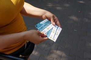 Na zdjęciu zbliżenie na dłonie kobiety która trzyma w rękach bilety na basen