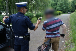 Na zdjęciu policjant kontrolujący trzeźwośc rowerzysty przy użyciu ręcznego urzadzenia do badania alkoholu w wydychanym powietrzu