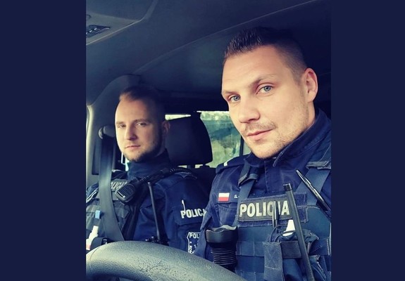 Na zdjęciu dwaj umundurowani policjanci wewnątrz radiowozu