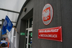 tablica przy wejściu do komendy miejskiej policji w świętochłowicach, w tle flagi związków zawodowych