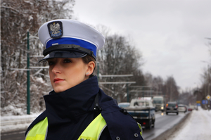 Policjantka ruchu drogowego obserwuje ruch na ośnieżonej drodze