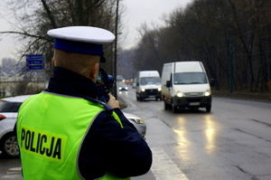 Policjant ruchu drogowego mierzy prędkość przy drodze