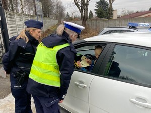 zdjęcia przedstawiają policjantów wręczających papierowe serca kierującym samochodami