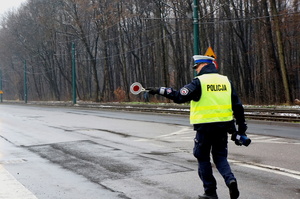 policjant ruchu drogowego w kamizelce odblaskowej zatrzymuje pojazd do kontroli z użyciem tarczy do zatrzymywania pojazdów - &quot;lizaka&quot;