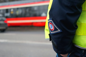 rękaw policjanta ruchu drogowego z logo &quot;R&quot;, w tle ulica i torowisko tramwajowe