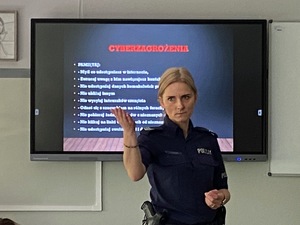 policyjna profilaktyk prowadzi prelekcję dla uczniów stojąc na środku sali