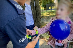 na zdjęciu policjantka wręcza gadżety dziewczynce na hulajnodze