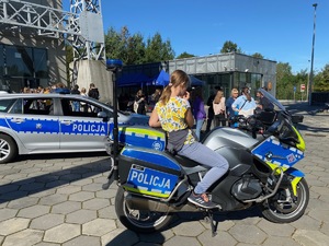 na zdjęciu motocykl ruchu drogowego z uczestniczką wydarzenia na tle radiowozu i wejścia do wieży kwk polska