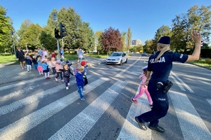 na zdjęciu policjantka uczy przedszkolaków przechodzenia przez jezdnię