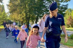 na zdjęciu policjantka uczy przedszkolaków przechodzenia przez jezdnię