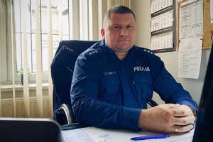 na zdjęciu policjant siedzący przy biurku