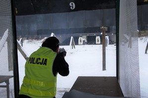 zdjęcie przedstawia policjanta strzelającego do tarczy na strzelnicy