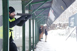 zdjęcie przedstawia policjanta strzelającego do tarczy na strzelnicy