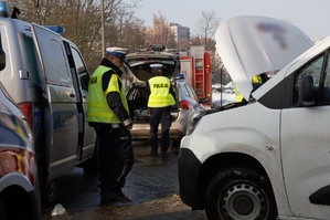 Zdjęcie przedstawia policjantów wykonujących czynności na miejscu zdarzenia drogowego