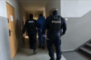 zdjęcie przedstawia policjantów prowadzących osobę zatrzymaną