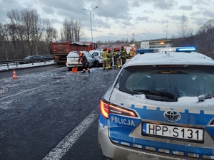 zdjęcie przedstawia rozbity samochód osobowy i wykonujące czynności na drodze służby