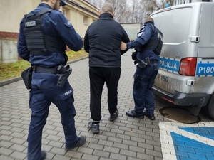 policjanci prowadzący zatrzymanego mężczyznę