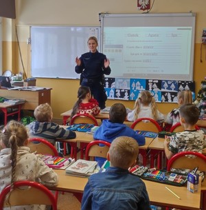 policjantka wygłaszająca prelekcje uczniom szkoły podstawowej