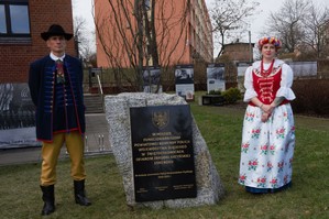 zdjęcie przedstawia: kobietę i mężczyznę ubraną w strój ludowy przy tablicy upamiętniającej