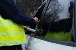 zdjęcie przedstawia policjanta podczas kontroli drogowej wręczającego mandat karny