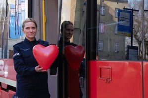 zdjęcie przedstawia: policjantkę stojącą przed tramwajem trzymającą serce