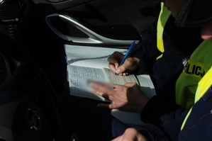 zdjęcie przedstawia: policjantka wypisująca mandat karny
