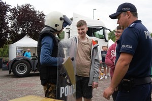 zdjęcie przedstawia: dzielnicowego podczas rozmowy z młodzieżą na pikniku