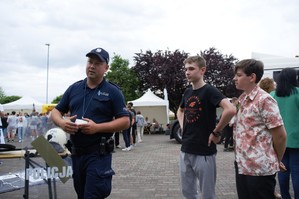 zdjęcie przedstawia: dzielnicowego podczas rozmowy z młodzieżą na pikniku