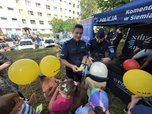 zdjęcie przedstawia: policjanta rozdającego dzieciom gadżety