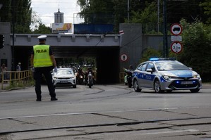 zdjęcie przedstawia: policjanta kierującego ruchem, policyjny radiowóz oraz kolumna przejeżdżających motocykli