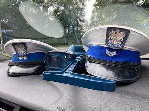 zdjęcie przedstawia czapki policjantów i miernik prędkości leżący na podszybiu radiowozu