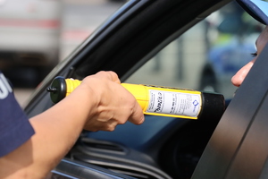 zdjęcie przedstawia policjanta badającego kierowcę na zawartość alkoholu w wydychanym powietrzu