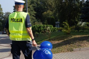 zdjęcie przedstawia policjanta trzymającego balony z napisem policja