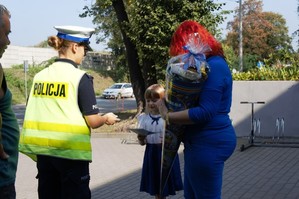 zdjęcie przedstawia policjantów rozdających odblaski i broszury profilaktyczne