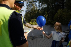 zdjęcie przedstawia policjantów rozdających odblaski i broszury profilaktyczne