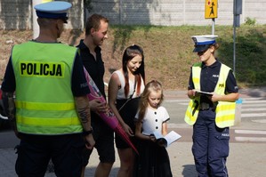 zdjęcie przedstawia policjantów rozdających odblaski i broszury profilaktyczne