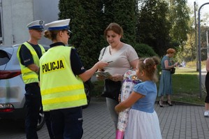 zdjęcie przedstawia policjantów rozdających odblaski i broszury profilaktyczne